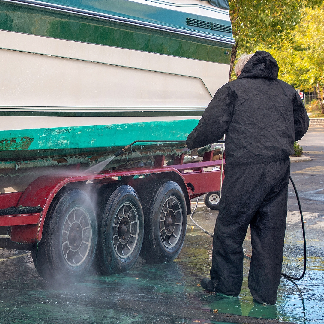 man cleaning boat trailer and boat